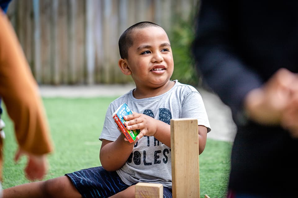 Young boy playing outdoors at childcare center in Onehunga