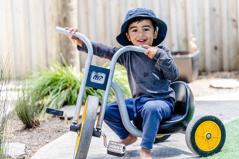 Young boy on bike, smiling at camera at our Onehunga childcare centre