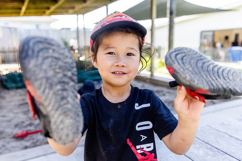 Young boy showing his shoes to the camera at Onehunga daycare