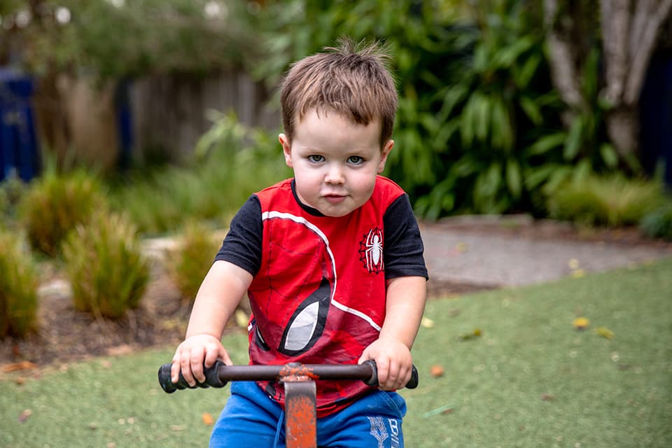 Young child in spiderman shirt on a bike