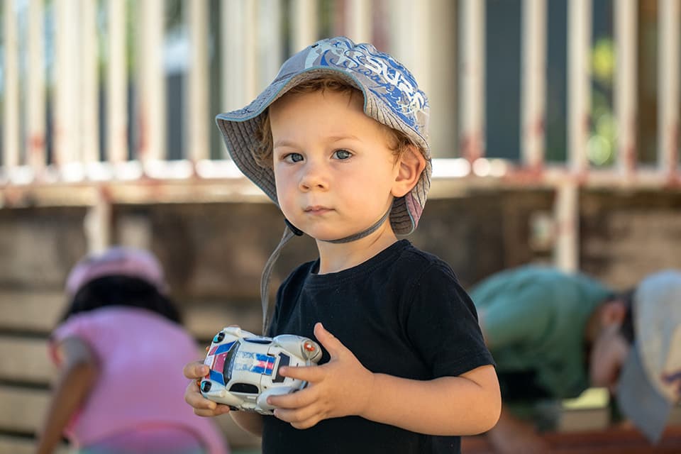 Young child in hat holding a toy car