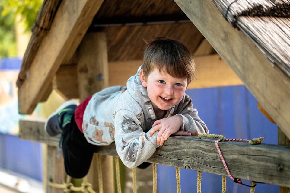 Kid climbing on top of house looking at camera